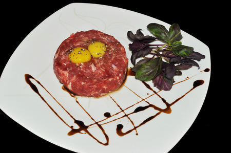 Steak Tartar. Ground beef and raw egg with herbs and spices on a marble background, top viewの写真素材