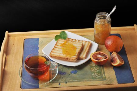 bread toast with orange marmalade. black mint tea in a transparent mug and blood oranges on a tray. Breakfast in the morning.の写真素材