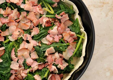 dish quiche before baking in the oven. bacon, spinach, thin crust. top viewの写真素材