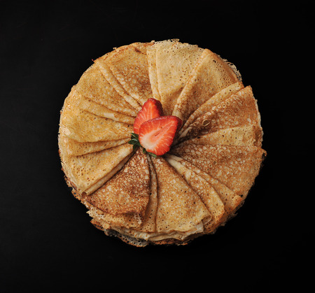 pancakes on a plate, folded triangle and strawberries on black background. top viewの写真素材
