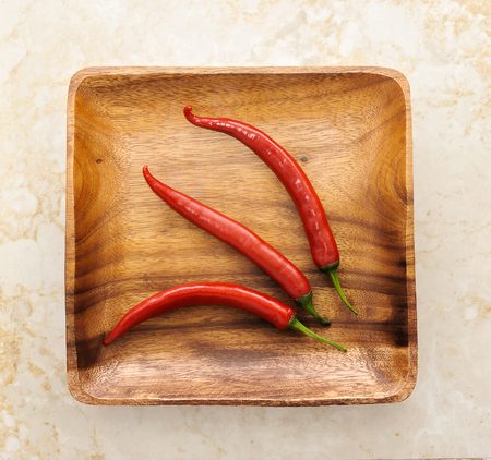 three cute red hot chili pepper on wood background