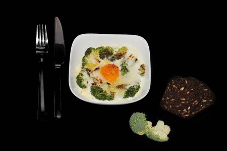 scrambled eggs with broccoli. Broccoli, bread with sunflower seeds and a knife with a fork on black background.の写真素材