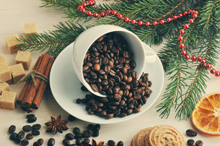 coffee beans poured into a mug at the Christmas backdrop from sugar, tree branches, cinnamon and anise on wooden backgroundの写真素材