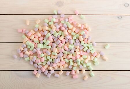 background from the scattered candy marshmallows on white wooden background - top view