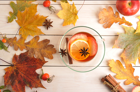 Cup of refreshing tea with lemon, Apple, rose hips and cinnamon in a transparent mug on a wooden background - top viewの写真素材