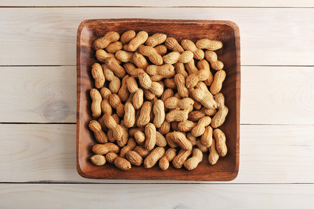 fruits peanut with shell in wooden plate on wooden background - top view