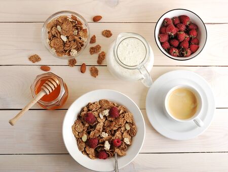 cereal with raspberries and almonds, milk, honey and coffee healthy Breakfast on wooden background - top viewの写真素材