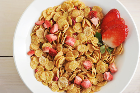 corn flakes with slices of strawberry in a bowl - top view, closeupの写真素材