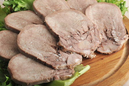beef tongue on a platter with lettuce leaves on a wooden background - top viewの写真素材