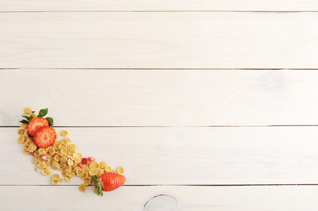 blank background with corn flakes and strawberries on wooden white background - top viewの写真素材