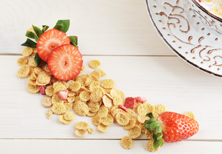 background with corn flakes and strawberries on wooden white background - top viewの写真素材