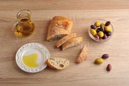 ciabatta with olives and yellow and purple olives with black olives, olive oil on wooden background - top viewの写真素材