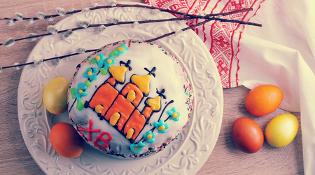 Easter cake with colored eggs and willow twigs on wooden background - top view in vintage aged style