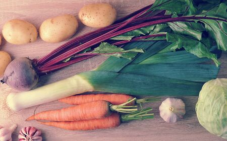 set of raw vegetables for healthy eating, leek, beets, potatoes, carrots, cabbage, garlic on a wooden background - top view in vintage aged styleの写真素材