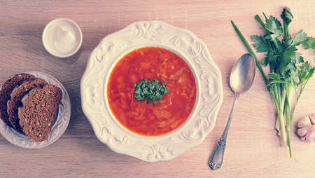soup in a bowl with dill, sour cream and black bread on wooden background - top view in vintage aged styleの写真素材
