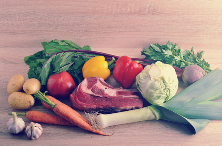 vegetable soup collection meat - potatoes, tomatoes, carrots, garlic, leeks, beets, pepper, parsley and beef on wooden background in vintage aged styleの写真素材