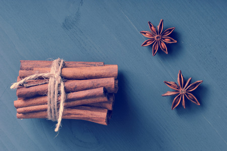 cinnamon sticks tied with a rope and the seeds of anise on dark rustic wooden background - top viewの写真素材