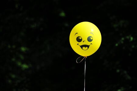 yellow balloon on a string with a painted face with a smileの写真素材