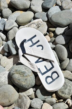 white Slippers with the word beach on the pebble beachの写真素材