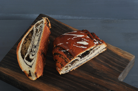 roll with poppy seeds, cut in half on wooden Boardの写真素材