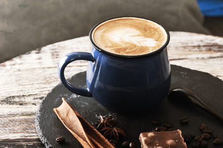 cappuccino in a mug with milk foam and cinnamon and chocolate on vintage tableの写真素材