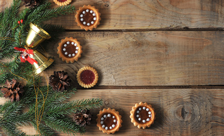 Christmas background with spruce branches and cones with cookies on a rough wooden background - top viewの写真素材