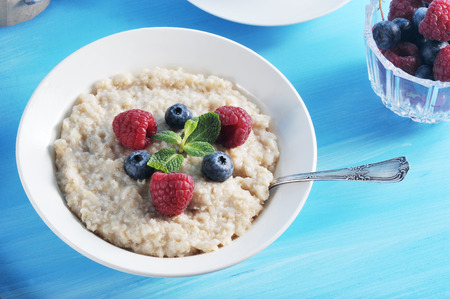 Breakfast oatmeal porridge on a blue background, oatmeal with berriesの写真素材