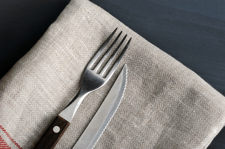 knife and fork on the linen tablecloth on wooden tableの写真素材