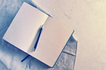 Open notebook on white marble background. Flat lay. Top view. Copy space.