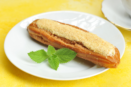 Eclair cake on a plate with a mint on a yellow background