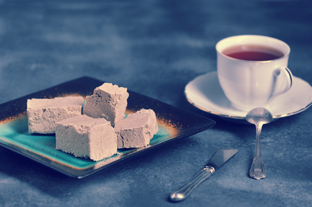 halva chopped into slices on a plate and tea in a mug on a dark background - oriental tea party in vintage styleの写真素材