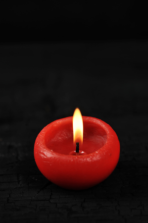 red candle with burning fire on black wooden rustic background - place for text, copyspaceの写真素材
