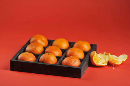 tangerines with in wooden box on a red background - side viewの写真素材