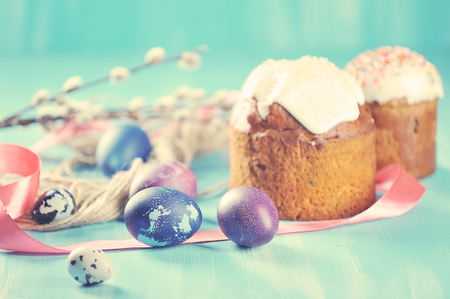 Easter holiday background - painted eggs on a blue background and Easter cake with willow branches in vintage styleの写真素材