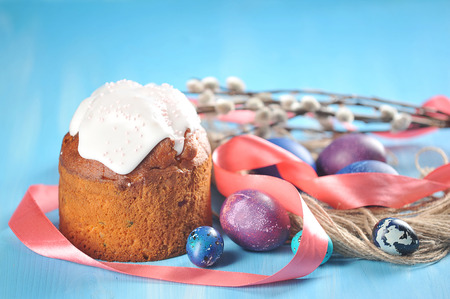 Easter holiday background - painted eggs on a blue background and Easter cake with willow branches