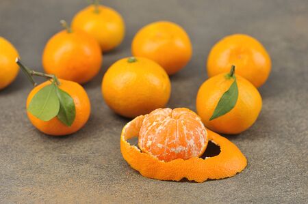 group of tangerines-whole tangerine with leaves and peeled tangerine with peel-close upの写真素材
