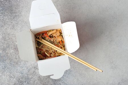 Chinese noodles in paper packaging with chopsticks on a gray background - Japanese cuisine-top viewの写真素材