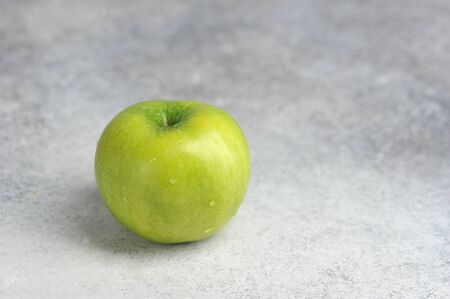 one green Apple on a gray background with space for text