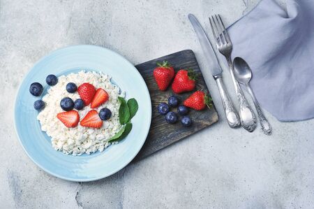quark and berries - blueberries, strawberries and mint with cottage cheese on a blue plate - top view - copy spaceの写真素材