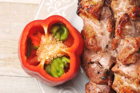 red pepper and pork skewers on skewers in a plate on a wooden background - top viewの写真素材