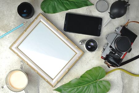photo composition - old film camera, lenses, an empty photo frame and a Cup of coffee - top view