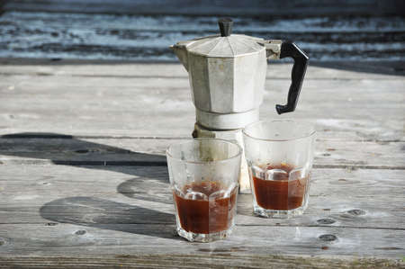 morning coffee-coffee pot and two glasses of coffee on a rough wooden backgroundの写真素材
