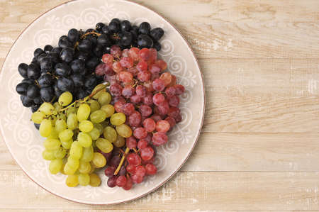 clusters of green red and black grapes on a plate - top viewの写真素材