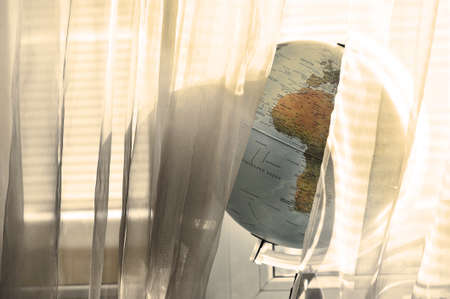 globe on the windowsill in the sun on the background of blinds