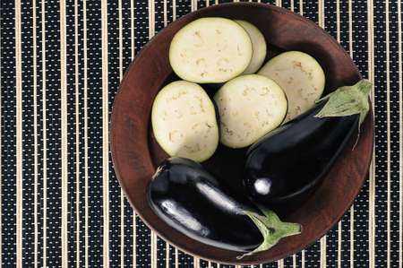 whole eggplants and sliced eggplants on a plate - top viewの写真素材