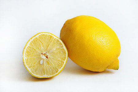 a whole lemon and half a lemon on a white backgroundの写真素材