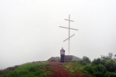 person goes to the cross on the top of the mountainの写真素材