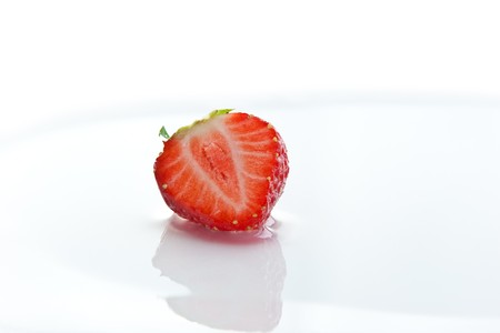 Single half ripe strawberry with reflection on water surfaceの写真素材