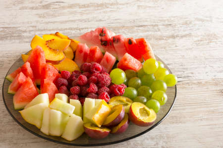 Fruit mix. Peach, grapes, apple, watermelon, melon, raspberry, plum. On white wooden background. Copy space, space for text.の写真素材