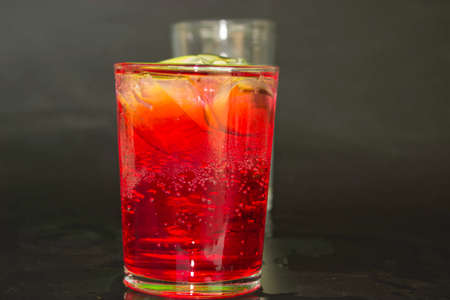 Red and green milk and ice in a glass on a black background.の写真素材